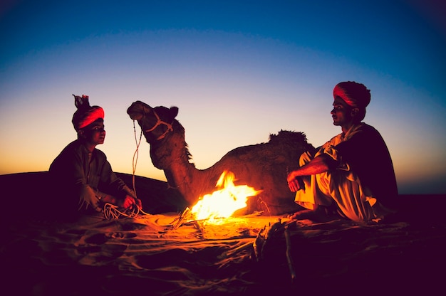 Indyjscy mężczyźni odpoczywają przy ognisku z wielbłądem