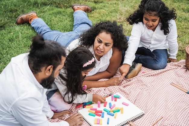 Indyjscy rodzice bawią się w miejskim parku bawiąc się drewnianymi zabawkami z córką i synem