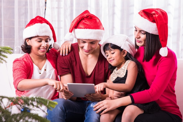 Indyjska azjatycka młoda rodzina świętująca Boże Narodzenie z prezentem podczas noszenia Santa Hat