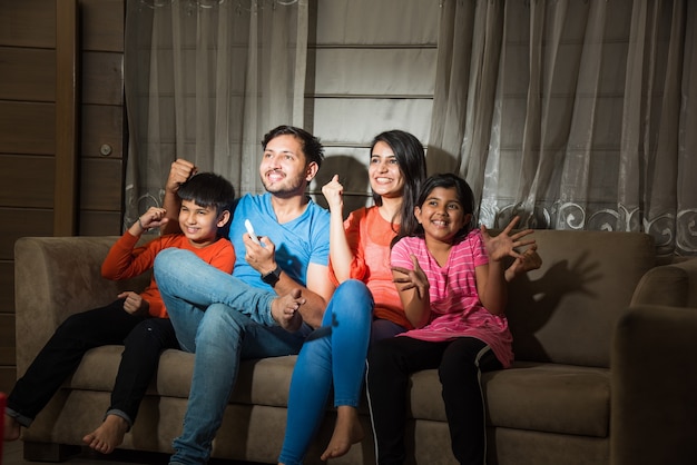 Indyjska Azjatycka Rodzina Składająca Się Z Czterech Osób Ogląda Telewizję Lub Telewizję Siedząc Na Kanapie Lub Kanapie
