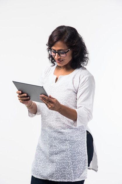 Indyjska dama w średnim wieku lub kobiety korzystające z komputera typu tablet stojąc na białym tle na białym tle, selektywne skupienie