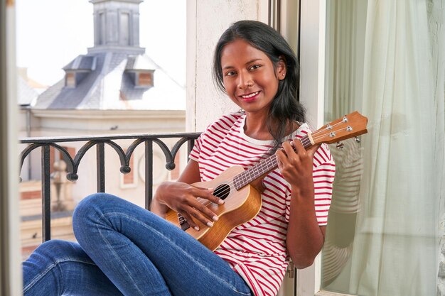 Zdjęcie indyjska kobieta grająca na ukulele na parapecie