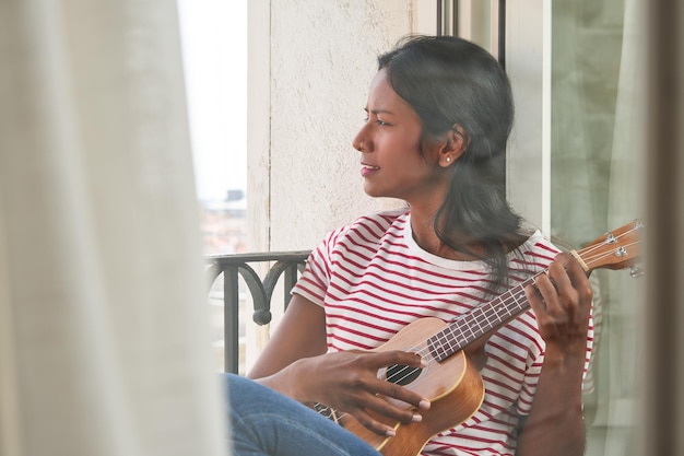 Indyjska kobieta grająca na ukulele na parapecie