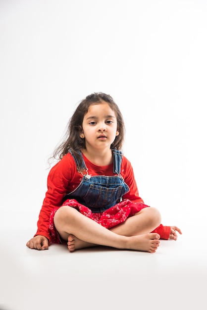Indyjska mała dziewczynka siedzi na białej podłodze