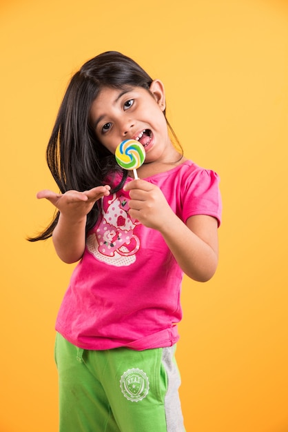 Indyjska mała dziewczynka z lolipopem lub loly popem, azjatycka dziewczyna i lolipopem lub lolypopem, figlarna indyjska urocza dziewczyna pozuje z lolipopem lub cukierkiem