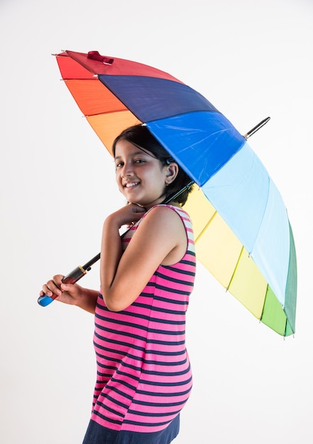 Indyjska mała dziewczynka z wielobarwnym parasolem, na białym tle nad białym