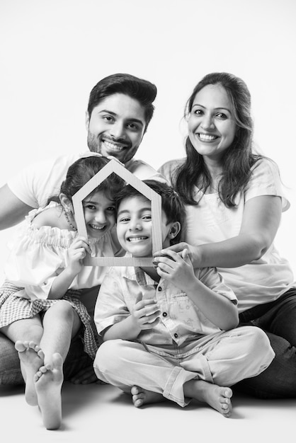 Indyjska rodzina Ojciec, matka, syn i córka trzymają papierowy model domu 3D - Real Istate Concept in India