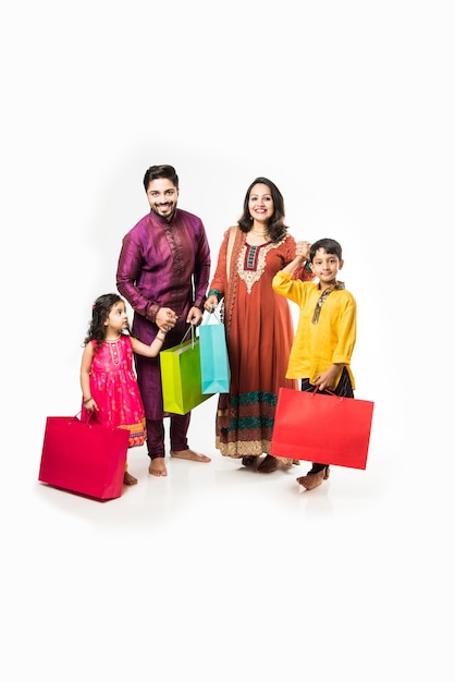 Indyjska rodzina świętująca Diwali lub Deepavali w tradycyjnym stroju z torbami na zakupy, stojąca na białym tle nad białym tłem