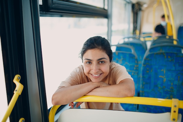 Indyjska uśmiechnięta pozytywna kobieta jeździ autobusem lub tramwajem komunikacji miejskiej