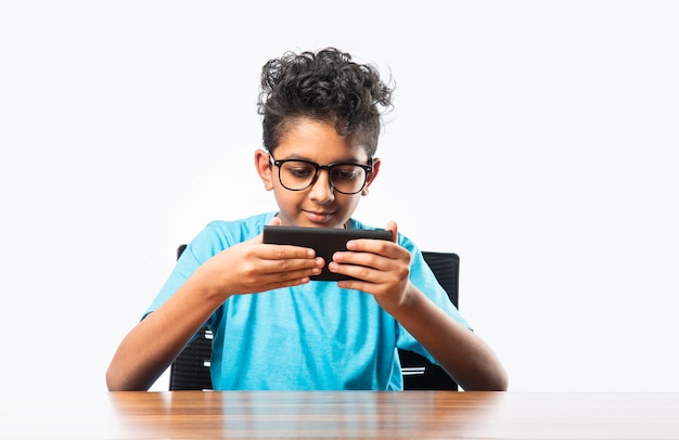 Indyjski azjatycki mały chłopiec lub dziecko używający smartfona do gier lub do edukacji