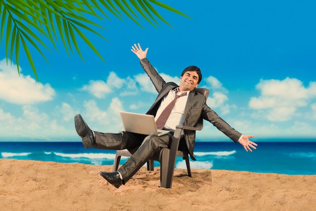 Indyjski azjatycki młody biznesmen relaksujący się lub pracujący na plaży, cieszący się przerwą w pracy