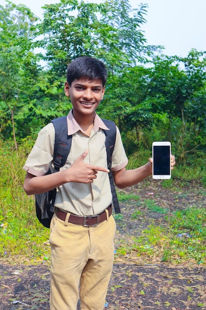 Indyjski chłopiec szkolny pokazujący koncepcję edukacji online na ekranie smartfona