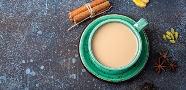 Indyjski gorący napój herbaciany z mlekiem i przyprawami w rustykalnej zieleni