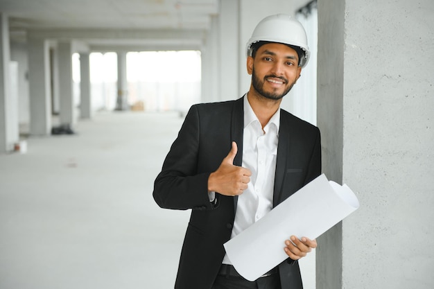 Indyjski kierownik budowy stojący w kasku myślący na budowie Portret pracownika fizycznego lub architekta rasy mieszanej