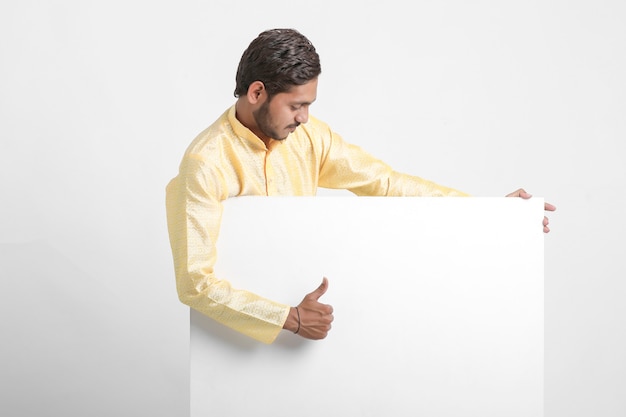 Indyjski mężczyzna trzyma białą tablicę stojącą nad białą ścianą