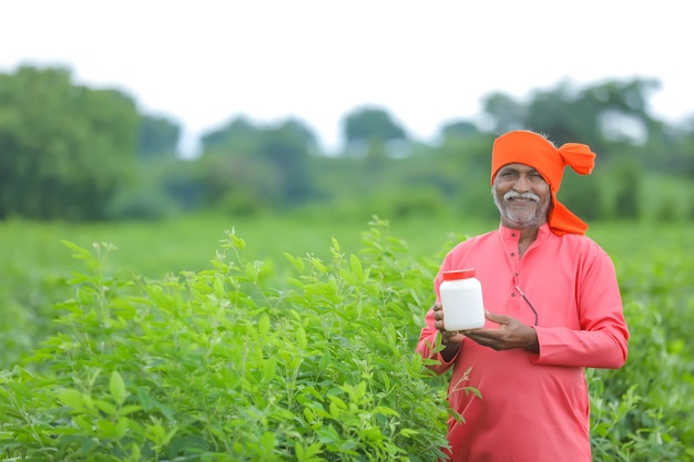 Indyjski rolnik pokazuje butelkę nawozu w polu