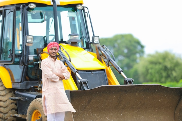 Indyjski rolnik stojący ze swoją nową maszyną do robót ziemnych.