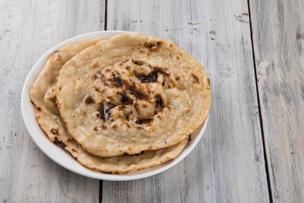 Indyjski specjalny płaski chlebek znany również jako maślany tandoori roti lub naan, podawany w białej ceramicznej ćwiartce