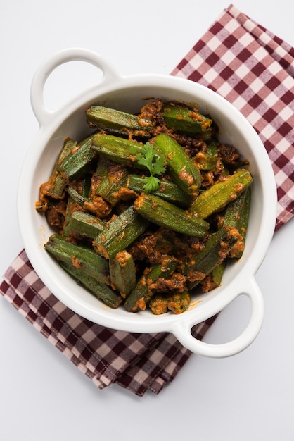 Indyjski styl Masala Sabji LUB Sabzi ze smażonej Bhindi LUB Okra znanej również jako Ladyfinger, podawane w misce na nastrojowym tle. selektywne skupienie