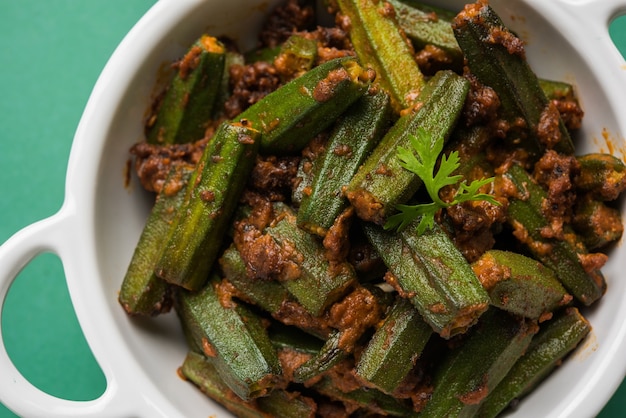 Indyjski styl Masala Sabji LUB Sabzi ze smażonej Bhindi LUB Okra znanej również jako Ladyfinger, podawane w misce na nastrojowym tle. selektywne skupienie