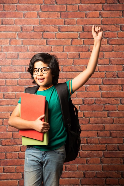 Indyjski Uczeń Płci Męskiej Z Spektrami, Trzymający Zeszyty I Tornister Przed ścianą Z Czerwonej Cegły