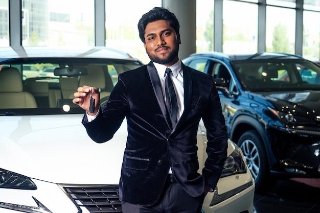 Indyjski wesoły sprzedawca samochodów pokazujący nowy salon z kluczami