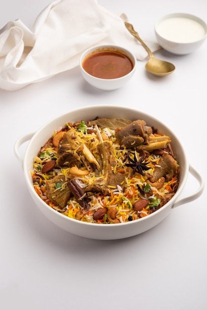 Indyjskie biryani z baraniny przygotowane w ryżu basmati podawane z dipem jogurtowym na nastrojowym tle, selektywne skupienie