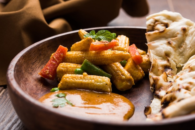 Indyjskie curry z kukurydzy i kukurydzy Masala przygotowane w czerwonym sosie podawane z pieczywem roti/naan LUB indyjskim. Na nastrojowym tle. selektywne skupienie