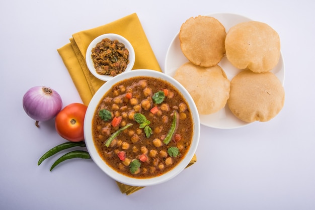 Indyjskie danie pikantne curry z ciecierzycy, znane również jako Chola lub Chana Masala lub powszechnie Chole, podawane ze smażonym puri lub poori na kolorowym lub drewnianym tle. Selektywne skupienie