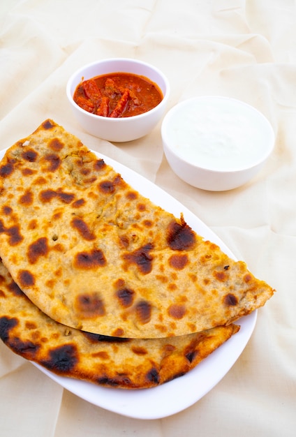 Indyjskie danie śniadaniowe Aloo Paratha podawane z twarogiem i marynatą