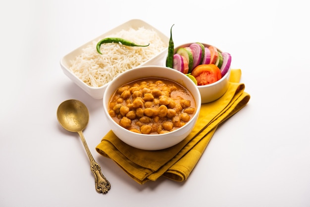 Indyjskie jedzenie chole chawal lub pikantne curry z ciecierzycy z ryżem zwykłym podawane z zieloną sałatą