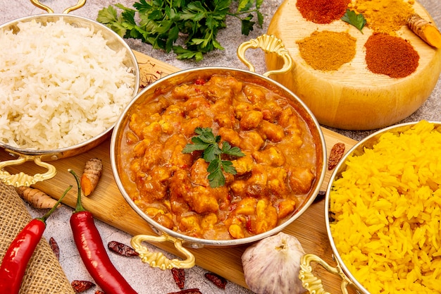 Indyjskie jedzenie. Kurczak curry w sosie pomidorowym z ryżem białym i żółtym, przyprawy: curry, kurkuma, papryka ostra i łagodna