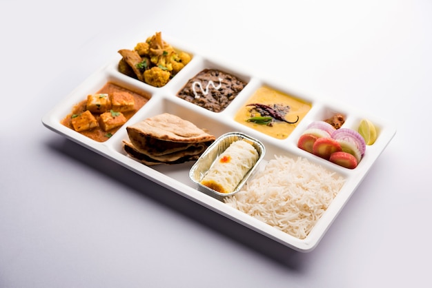 Indyjskie jedzenie wegetariańskie Taca Thali lub Parcel z przegródkami, w której podawana jest paneer, dal makhani lub parka, aloo-gobi sabji, chapati i ryż z bengalskim słodkości