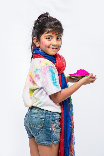 Indyjskie małe dzieci, przyjaciele lub rodzeństwo świętujące święto Holi z kolorem gulal lub proszku, słodyczami, pichkari lub sprayem, odizolowane na białym tle