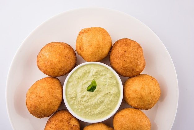 Indyjskie przekąski Aloo Bonda lub batata vada lub urad daal vada lub pakoda lub pakora. Podawany z zielonym chutneyem. Selektywne skupienie