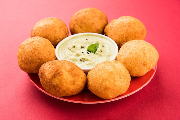 Indyjskie przekąski Aloo Bonda lub batata vada lub urad daal vada lub pakoda lub pakora. Podawany z zielonym chutneyem. Selektywne skupienie