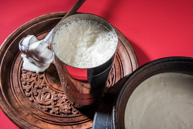 Zdjęcie indyjskie słodkie lassi składające się z mleka, twarogu, cukru i soli zmieszanych z kostkami lodu, podawane w jumbo stalowej szklance, przygotowane w tradycyjnym glinianym garnku