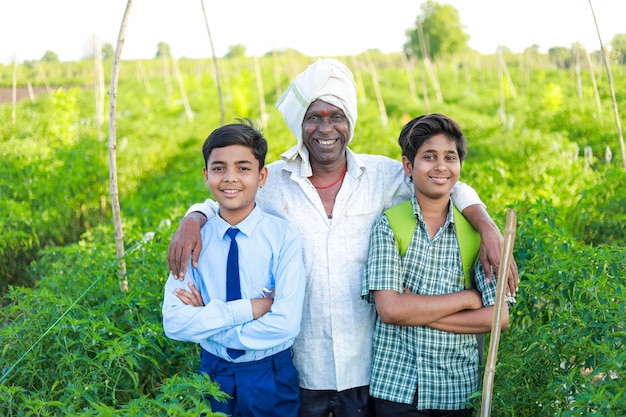 Indyjskie trzy osoby stojące w gospodarstwie rolnym i jego dwaj synowie w szczęśliwej rodzinie na farmie