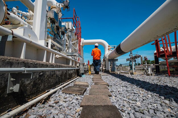 Inspekcja przez pracownika w przypadku długich rur stalowych i łokcia rury w stacji fabryki ropy naftowej podczas zaworu rafinerii rurociągu.