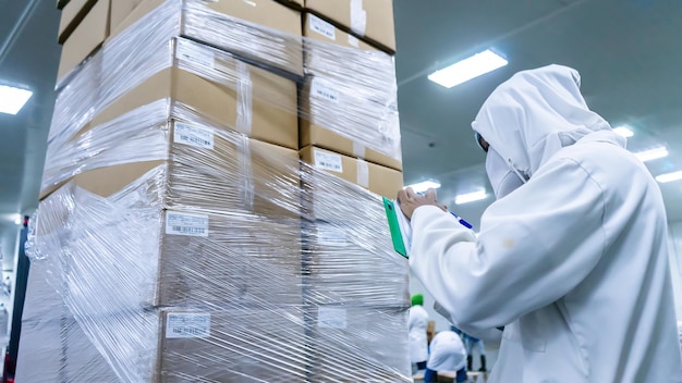 Zdjęcie inspektor bezpieczeństwa i jakości inwentaryzujący produkt zapakowany w kartony w zakładzie przetwórstwa spożywczego