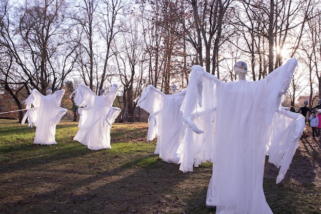 Instalacja wielu przerażających białych duchów z dużymi ramionami i całym ciałem w parku w dzień Halloween