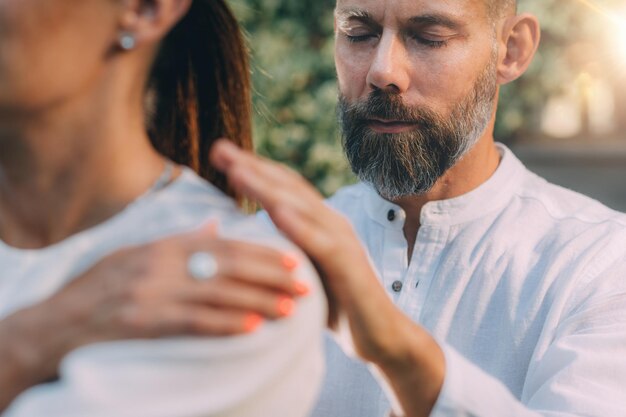 Zdjęcie instruktor reiki z rękami na ramionach uczestnika kursu