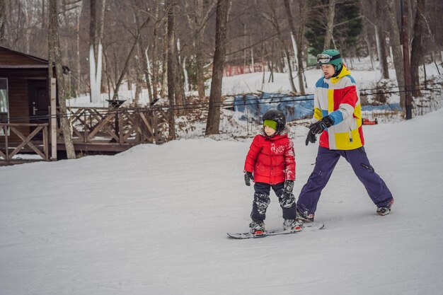 Instruktor snowboardu uczy chłopca jeździć na snowboardzie Zajęcia dla dzieci w zimie Sporty zimowe dla dzieci Styl życia