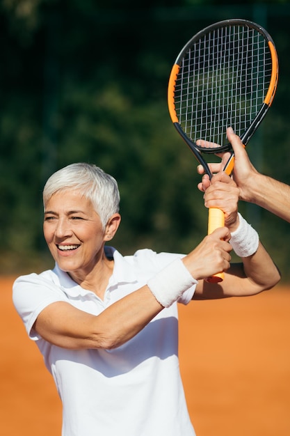 Instruktor tenisa uczy starszą kobietę, jak grać w tenisa