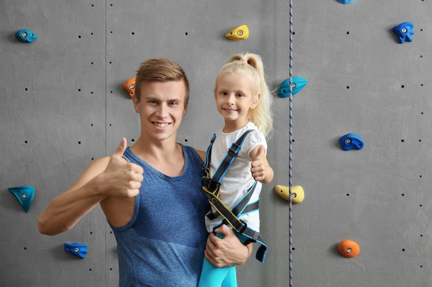Instruktor trzyma małą dziewczynkę w siłowni wspinaczkowej