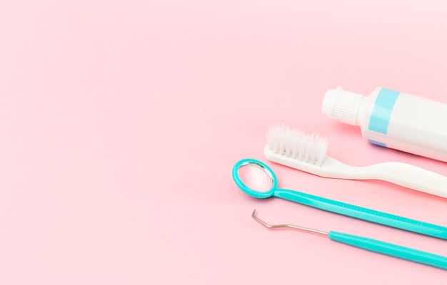 instrumenty dentystyczne szczoteczka do zębów i pasta na różowym tle
