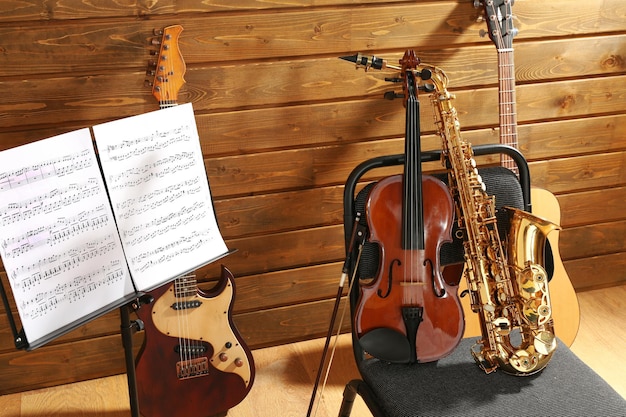 Instrumenty muzyczne na krześle i uchwycie na notatki na drewnianym tle
