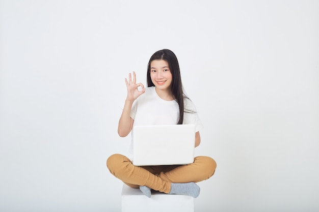 Inteligentna Atrakcyjna Młoda Kobieta Używa Laptopa Siedzącego Ze Skrzyżowanymi Nogami Na Szarym Tle Studia