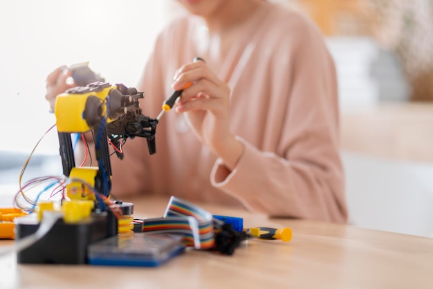 Zdjęcie inteligentna azjatycka programistka ucząca się ramienia robota ai kodowania kabla płytki elektronicznej w stem steam, próbuje przetestować swoje autonomiczne ramię robota z czujnikami za pośrednictwem platformy arduino w domu