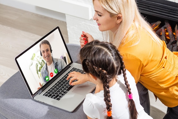 Inteligentna mała przedszkolanka ogląda lekcję online i komunikuje się z nauczycielem w domu, małe dziecko uczy się w Internecie za pomocą połączenia bezprzewodowego laptopa.